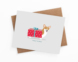 Illustrated happy holiday corgi wrapped in a present card by LaCorgi.